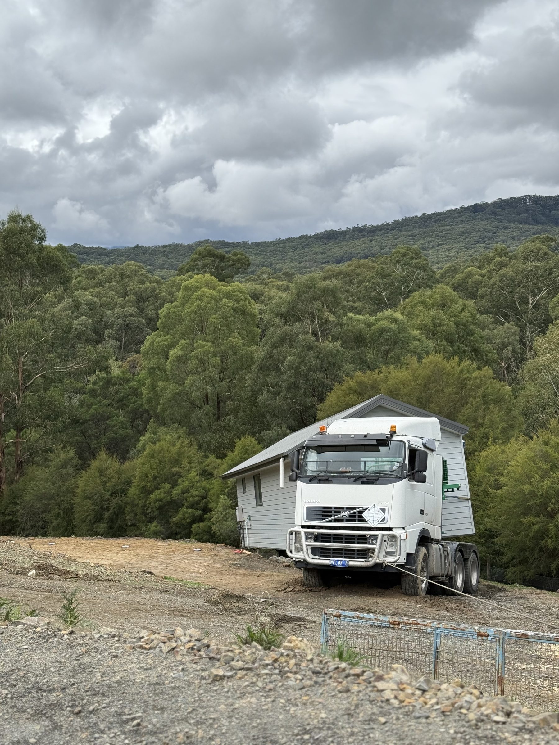 Truck delivering a relocated house to a hilltop site